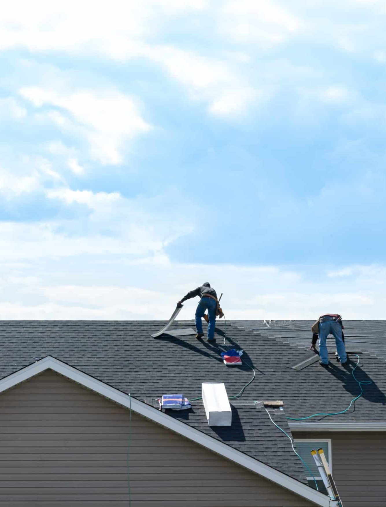 4 construction workers fixing roof against clouds blue sky, install shingles at the top of the house. Renovate, improvement, build home exterior by professional teamwork. Safety and protection concept